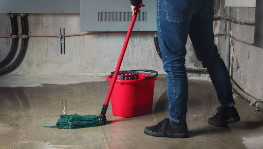 Homeowner mopping basement floor that was flooded from plumbing issue.