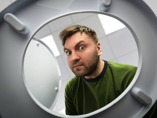 A concerned man looking into a toilet bowl.
